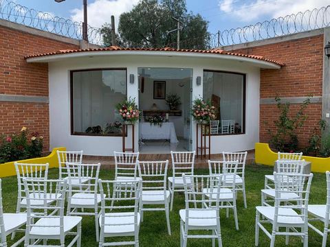 Capilla blanca del jardín con sillas Tiffany blancas montadas sobre el pasto para una ceremonia