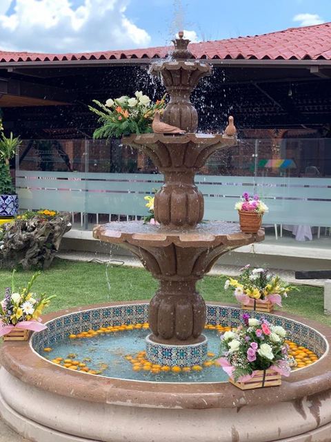 Fuente de cantera con arreglos florales blancos y el agua corriendo, de día