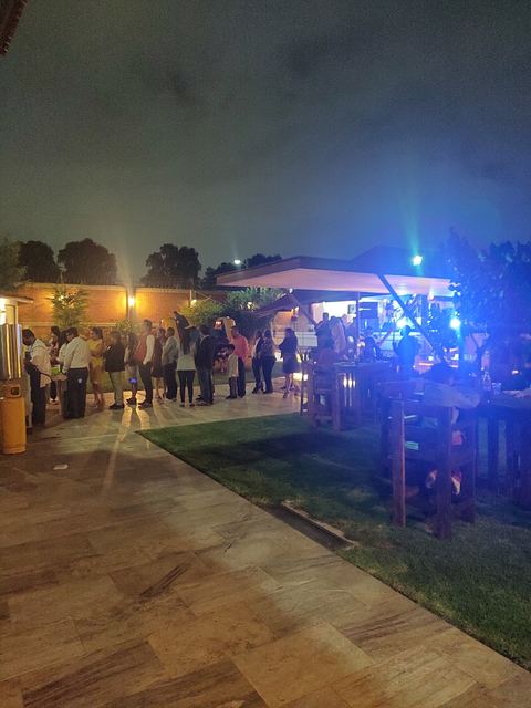 El jardín de noche durante un evento, con los invitados bajo el techo iluminado
