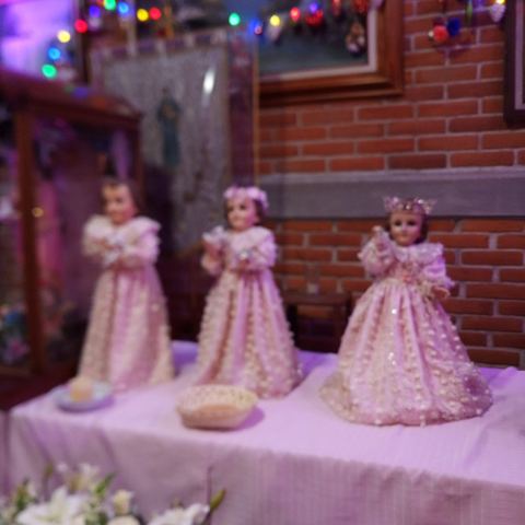 Mesa decorada para un bautizo con figuras vestidas de blanco y flores