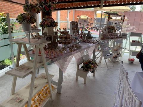 Mesa de postres montada con escalones de madera, flores y bocadillos
