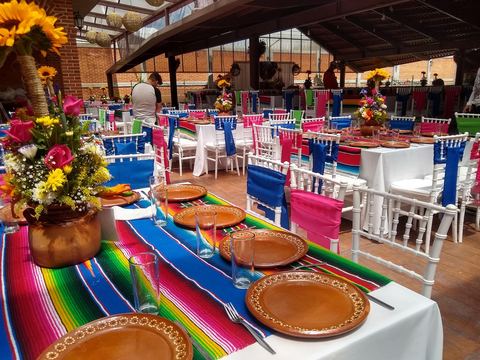 Montaje mexicano con centros de girasoles, mantelería de colores y vajilla de barro
