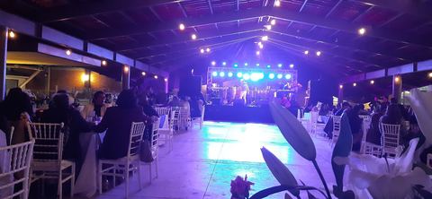 Pista de baile iluminada de noche con el escenario al fondo y sillas Tiffany blancas alrededor